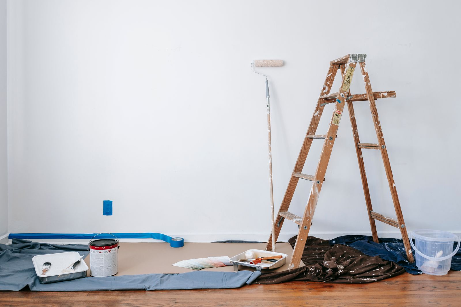 A St. George home interior taped off and prepped for painting — paint roller, ladder, color swatches, and a fresh white wall