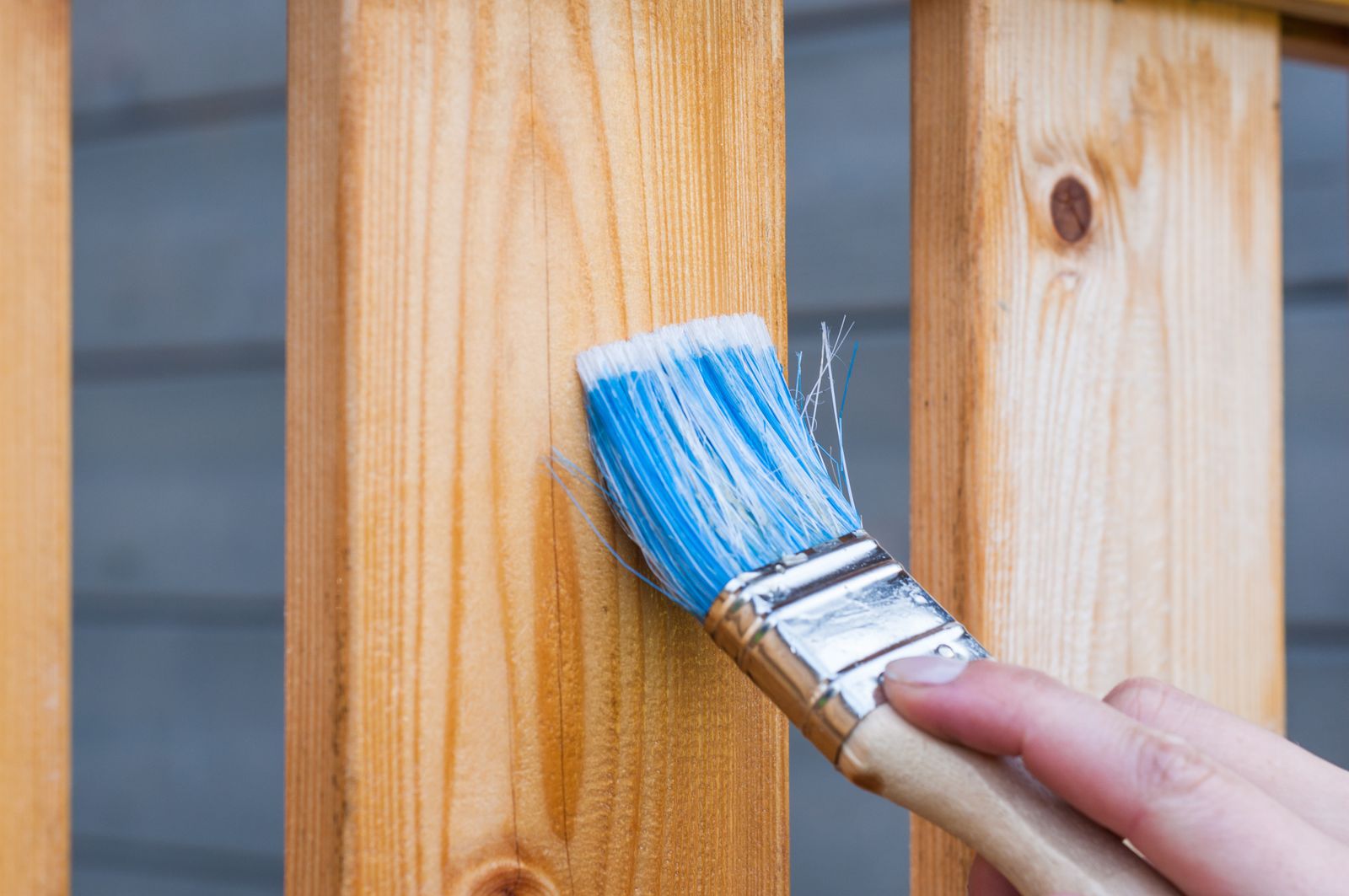 Close-up of a paint brush coating exterior wood trim with an even stroke